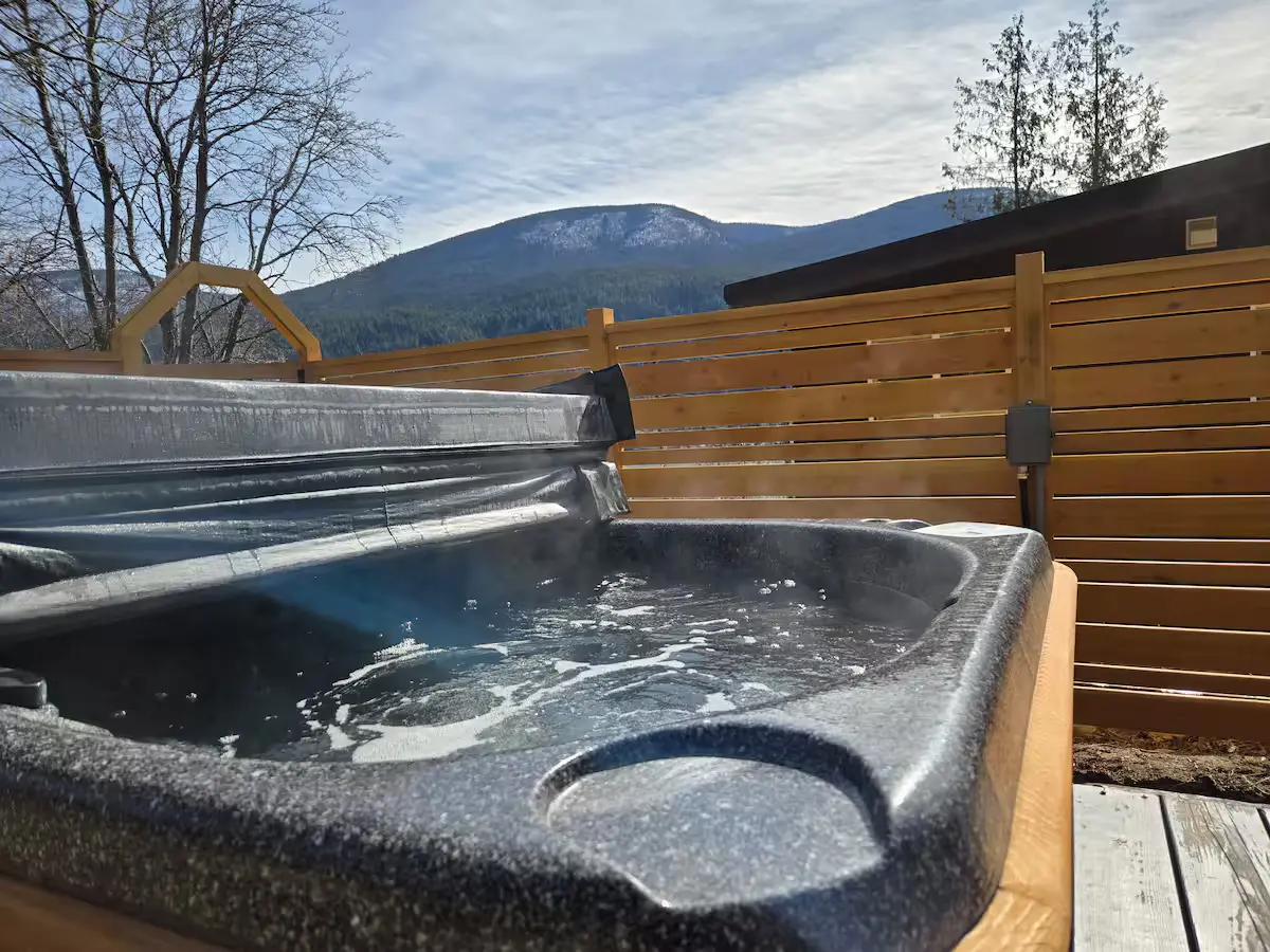 Covered deck with outdoor dining table and swing chairs overlooking Kootenay Lake