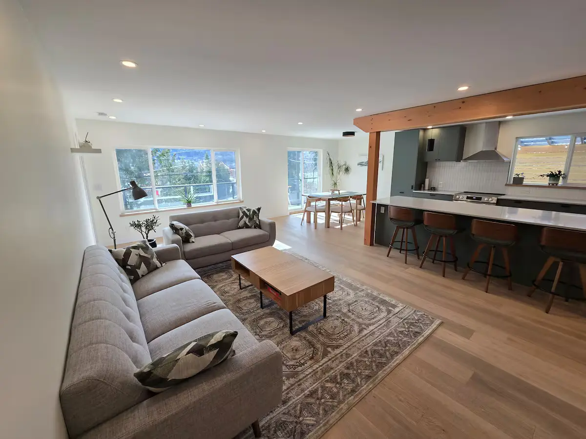 Open-concept living, dining and kitchen space with large windows at The Treehouse Nelson